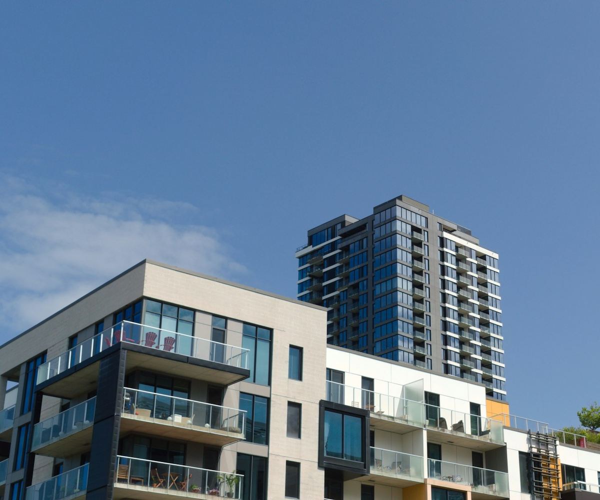 Modern condominium buildings with glass balconies under a clear blue sky